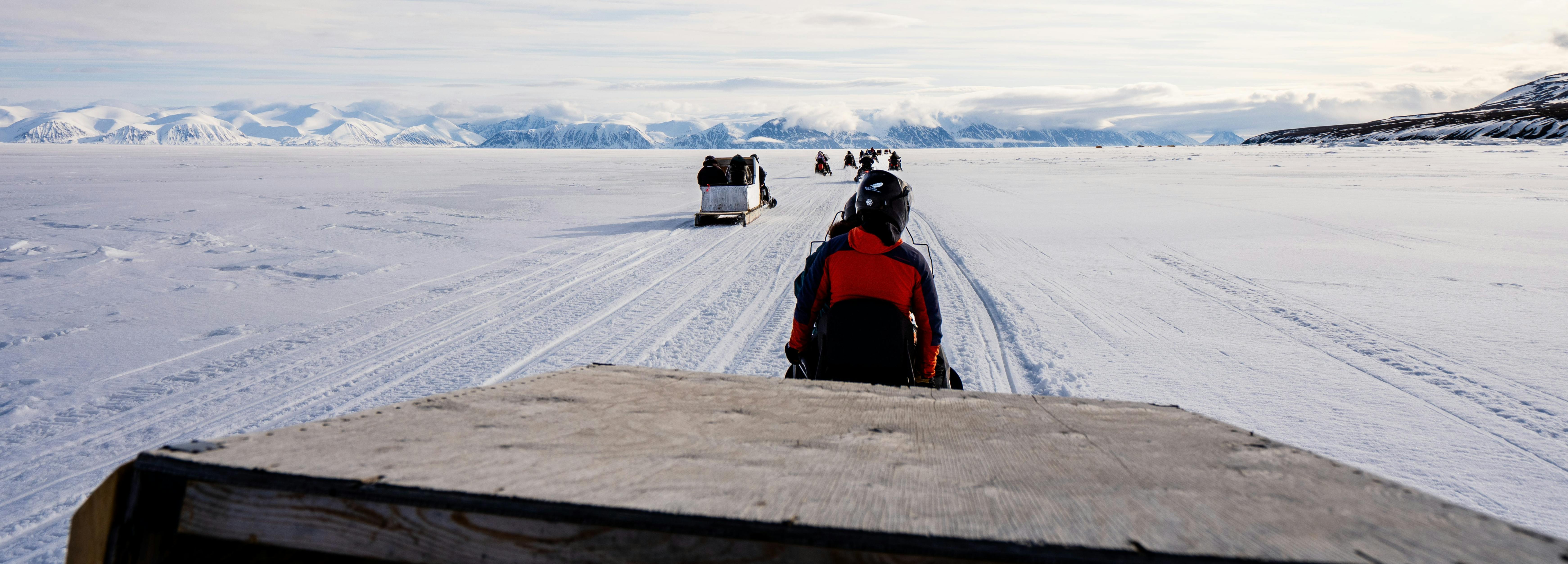 Cargo being towed via snowmobile across sea ice of Tallurutiup Imanga National Marine Conservation Area.