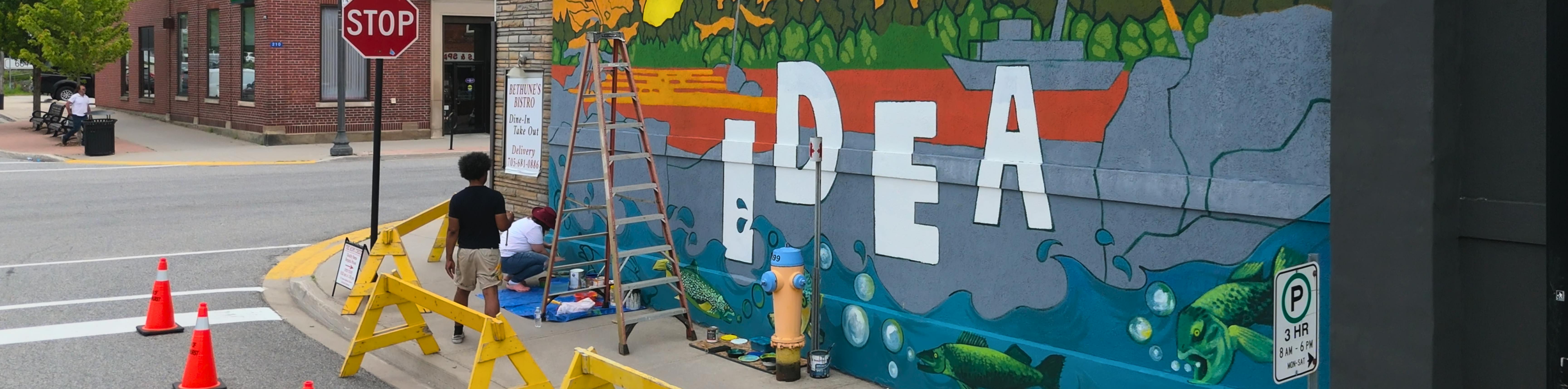 Artists painting the IDEA mural in Gravenhurst