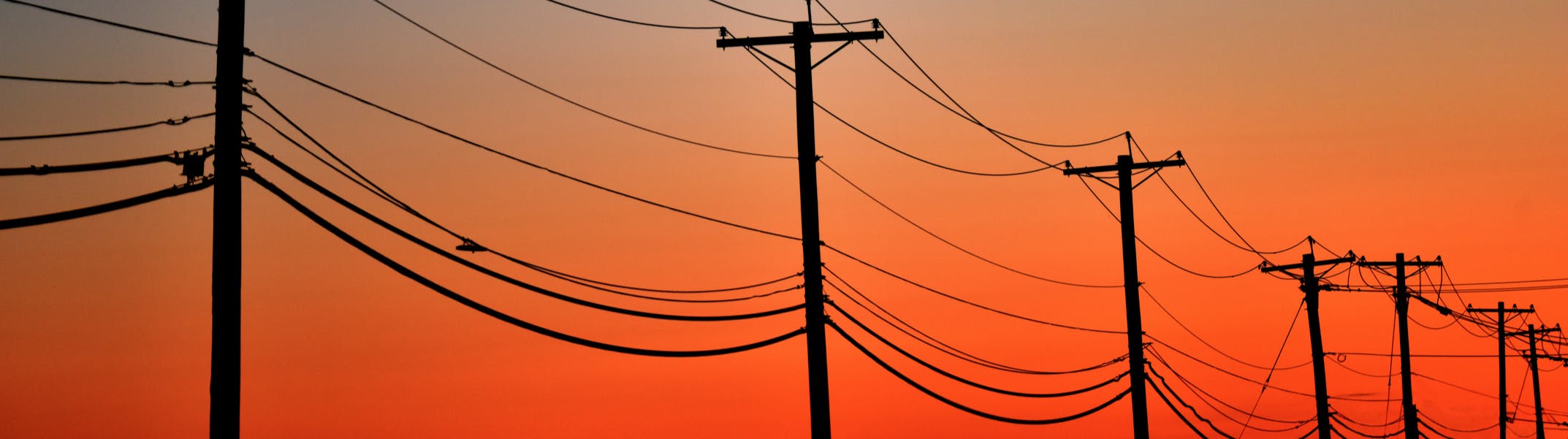 Looking at Electricity distribution poles as the sun sets