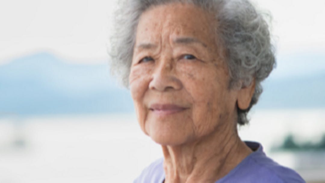 Photograph of older Asian woman looing at the camera.