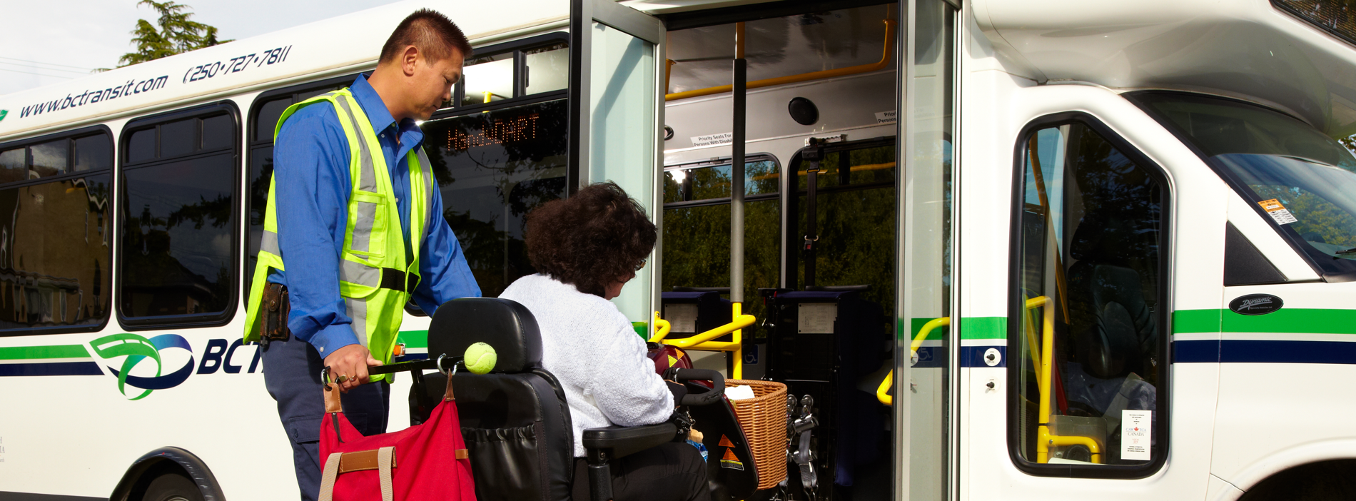 A picture of a handyDART drive supporting a rider in a power chair up the bus ramp