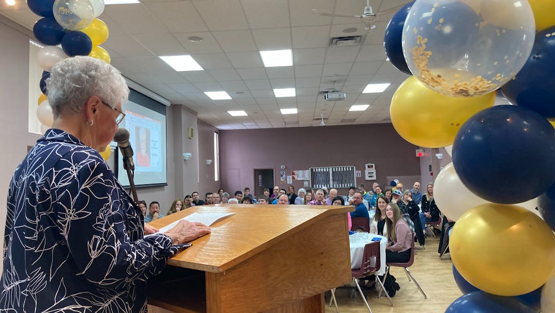 A lady is making a speech on the stage in front of the croud.