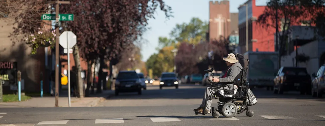 Person in motorized wheelchair crossing the street.
