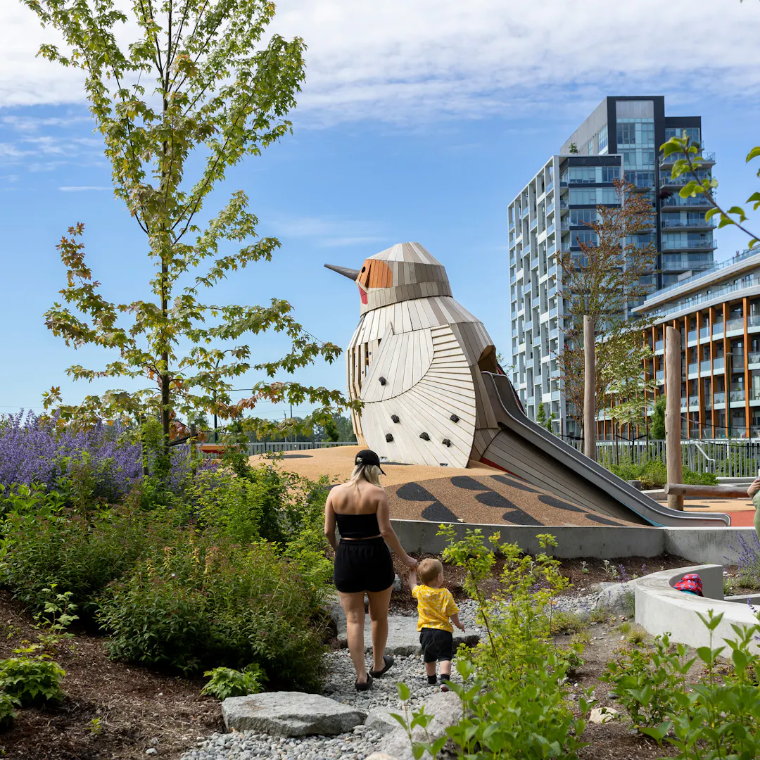 Woman and child walking in park toward bird play structure