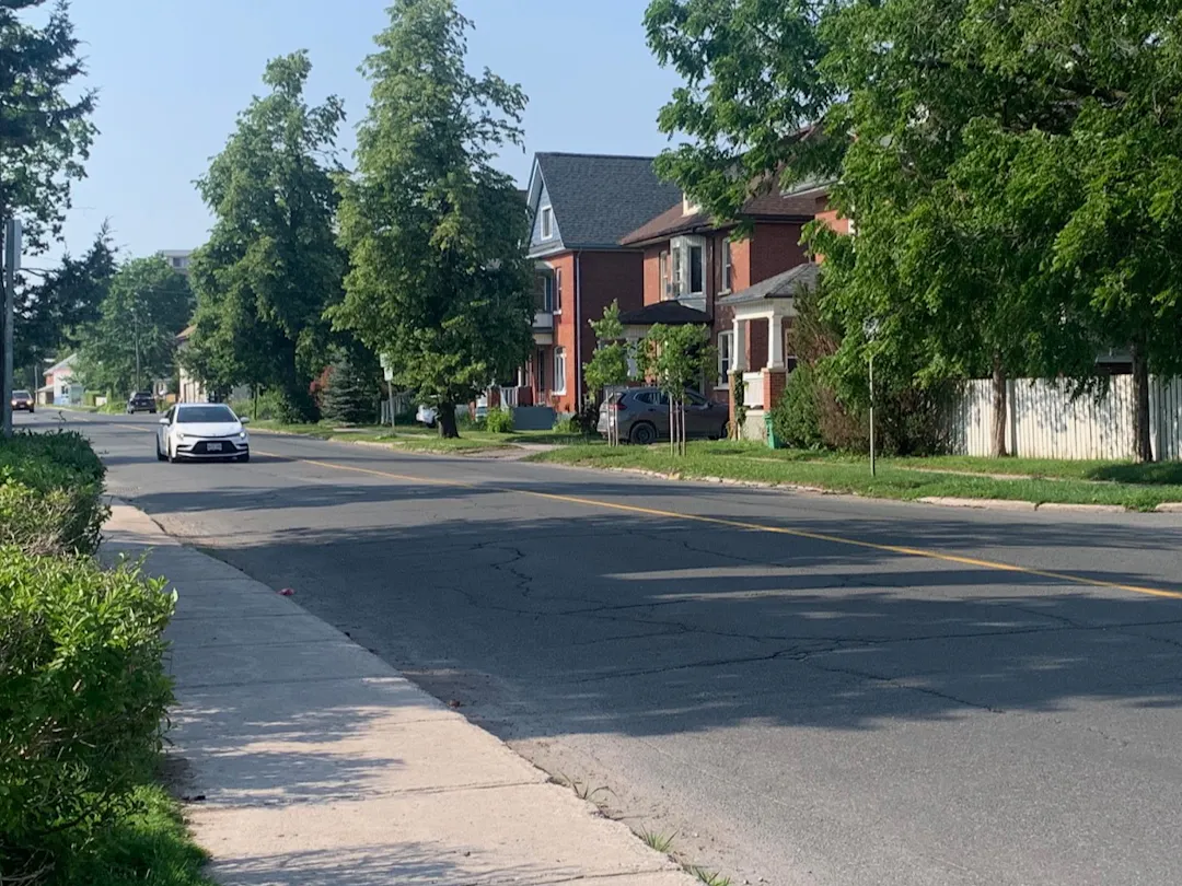 Image of Park Street looking north at Hunter Street. The image shows a leafy green residential neighbourhood and two cars. 