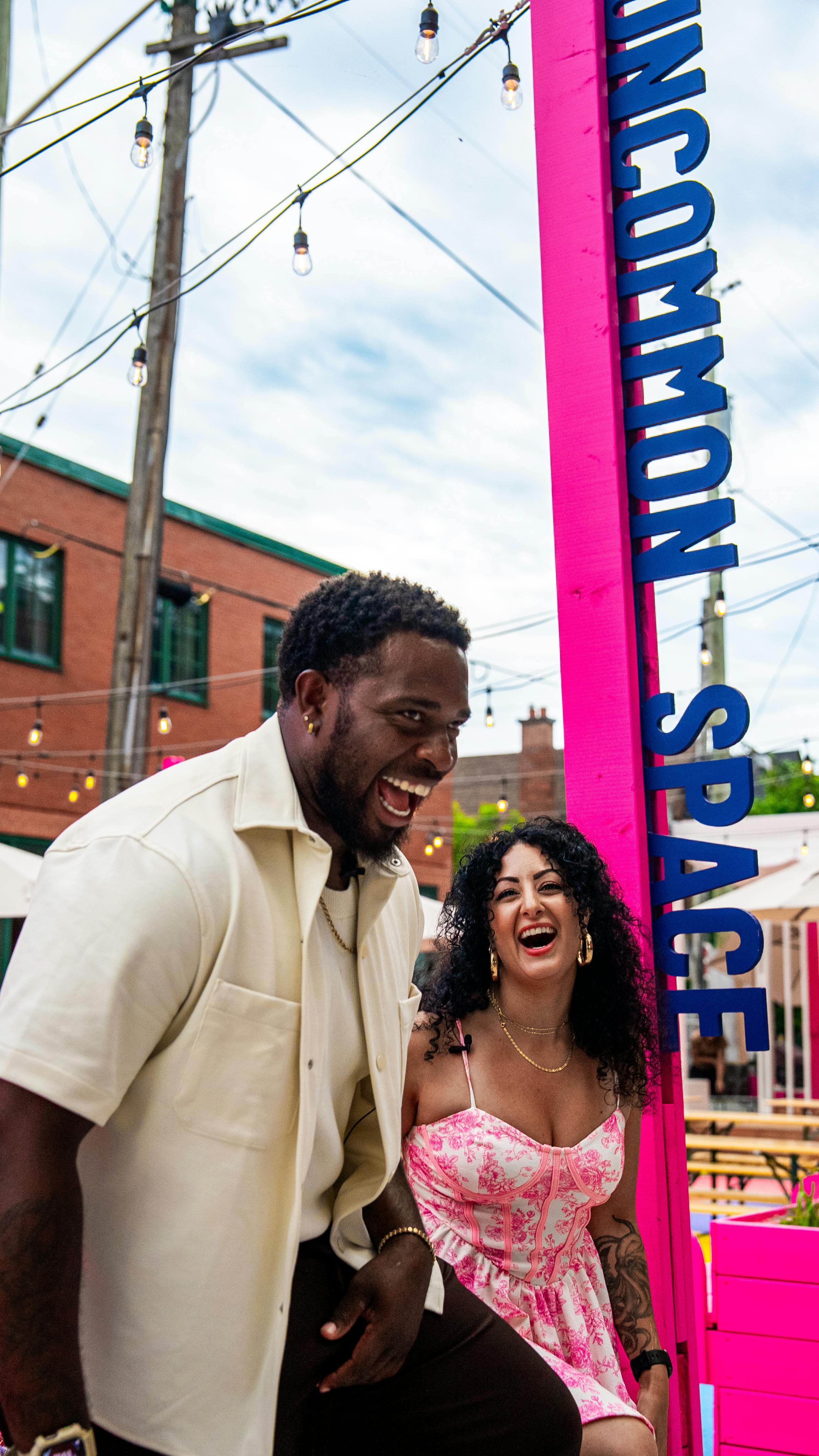 Two people laughing beside a sign that reads "Uncommon Space"