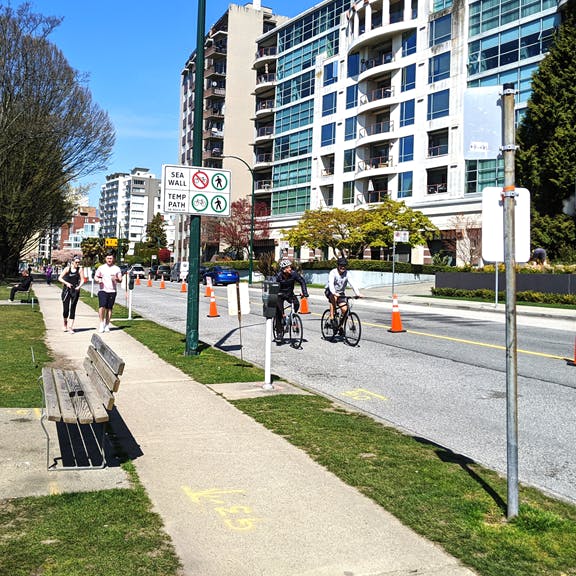 People running on the sidewalk, people cycling on the road in the Room to Move area on Beach Avenue