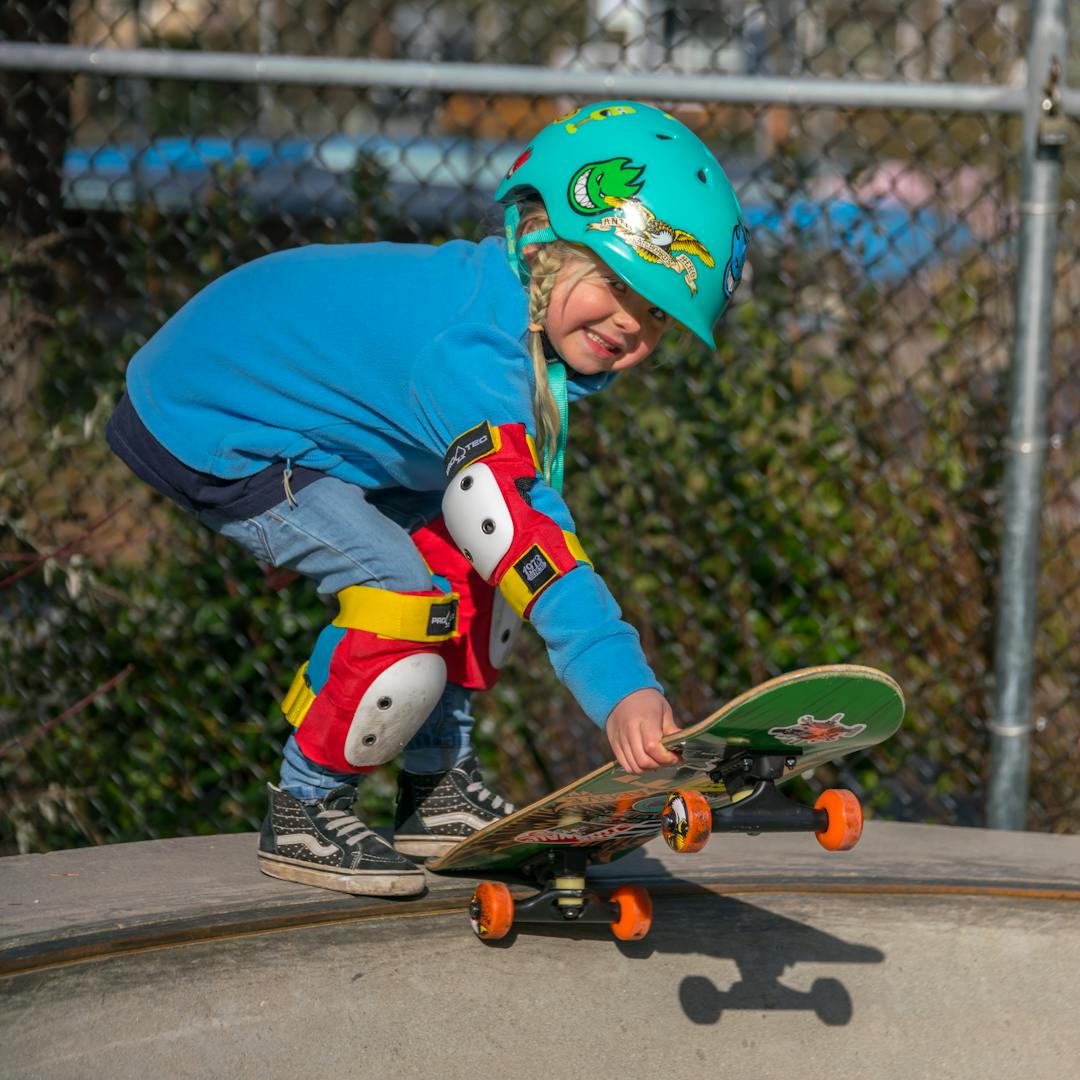 Young girl Ivy skateboarding at Mount Pleasant Skate Park on a sunny day with a big smile