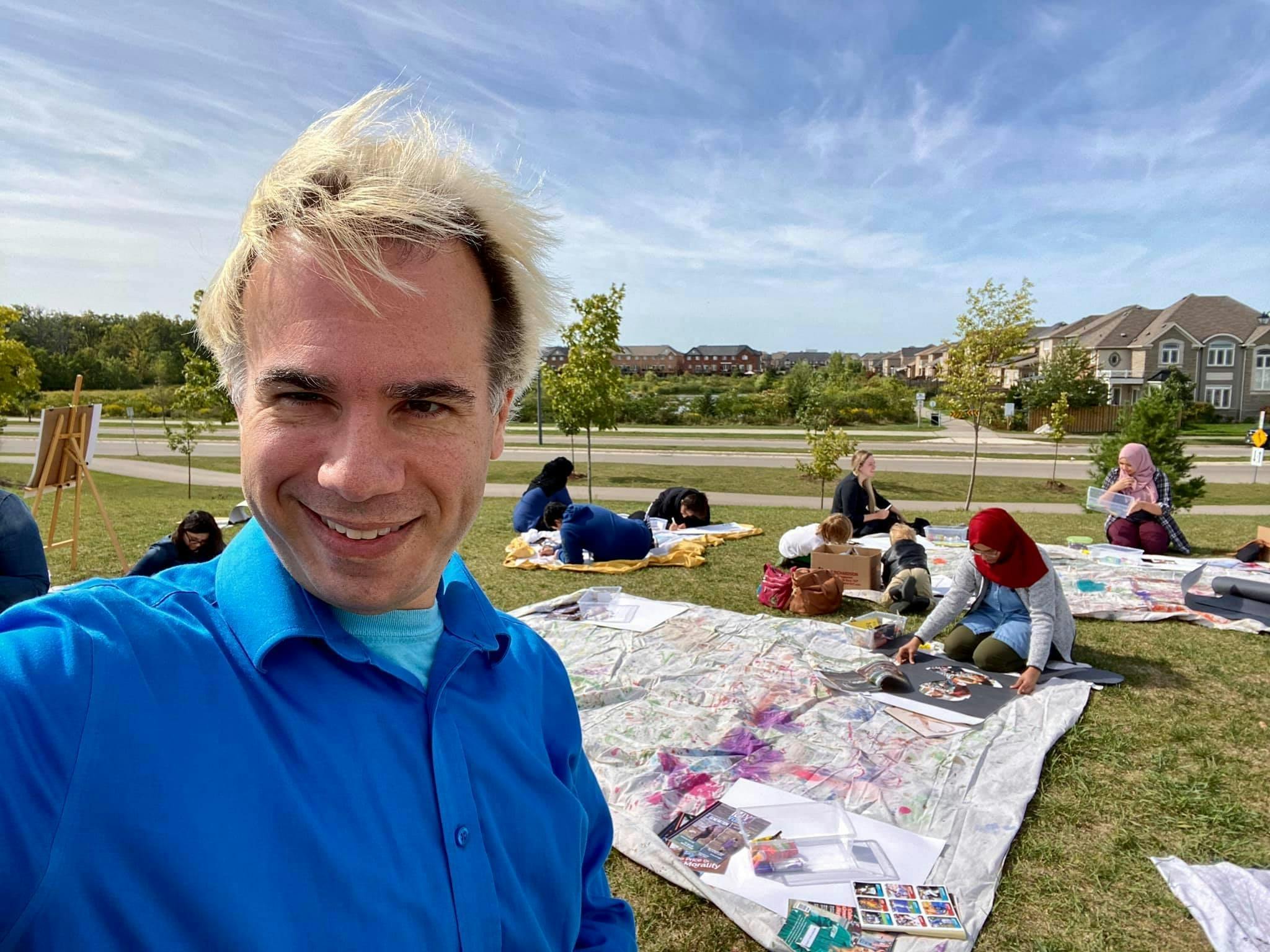 Councillor Di Lorenzo taking a selfie while participants create artwork in the background. 