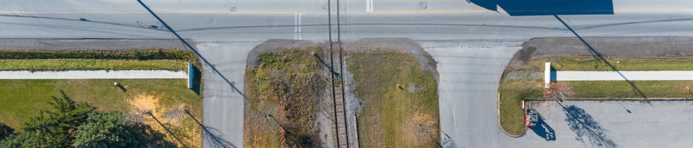 An aerial photo looing straight down at a sidewalk that stops before a train track crossing.