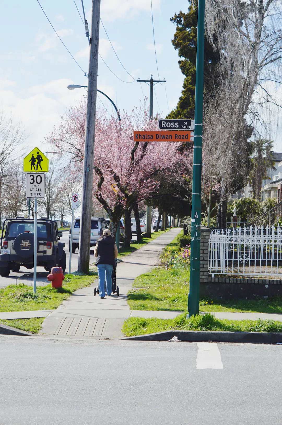 a person with a stroller walking away on the sidewalk at the intersection of Ross Street and E 59th Avenue 