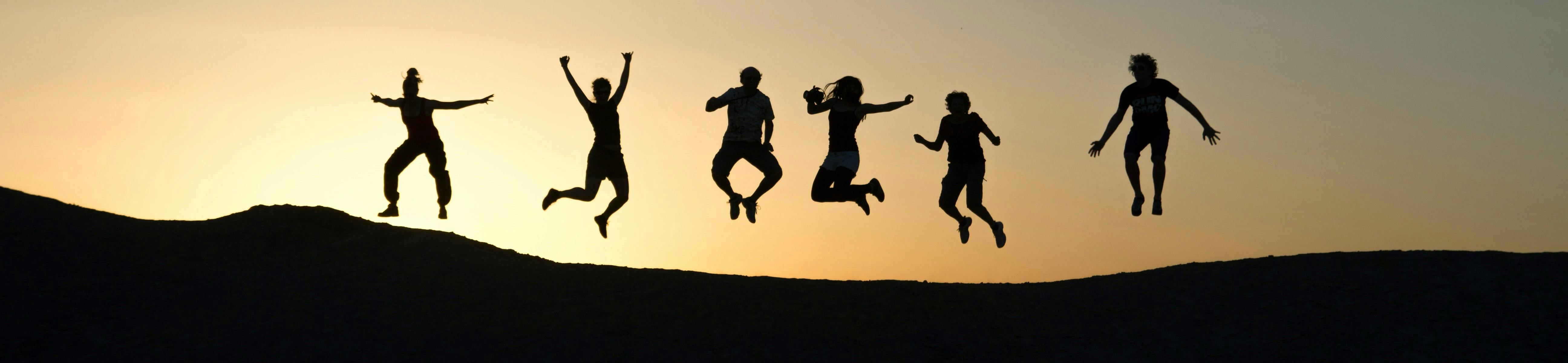 people jumping against a sunset
