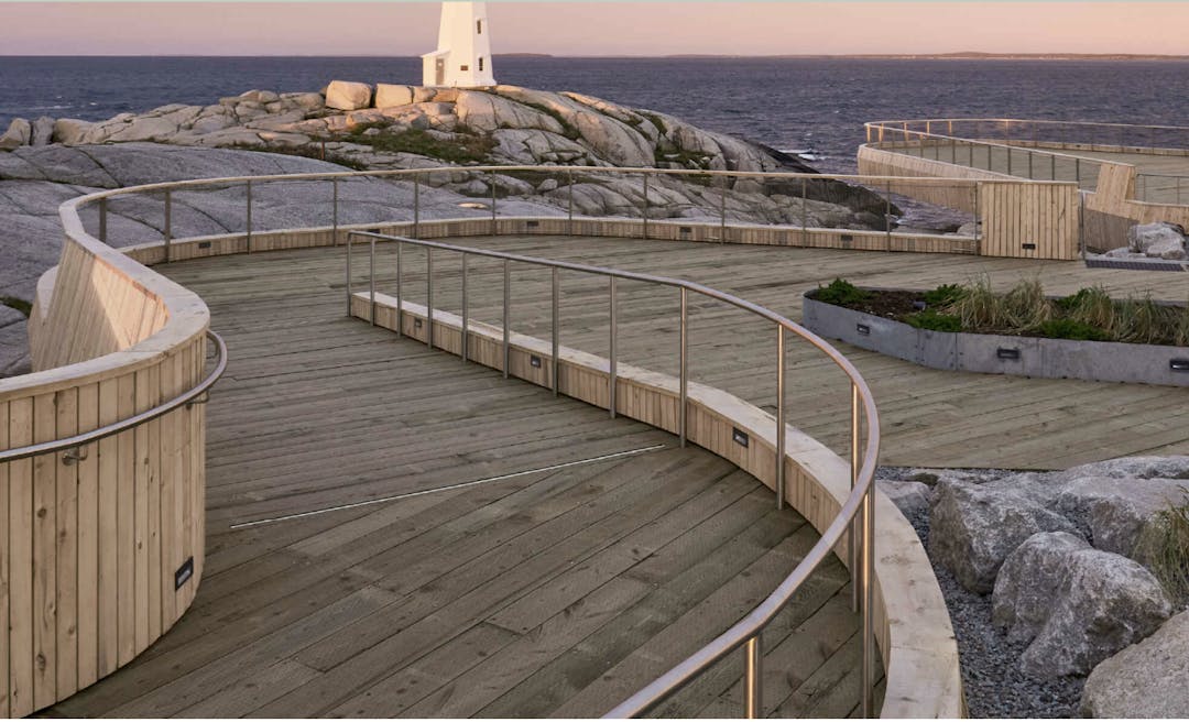 Wooden ramp to Peggy's Cove, curved around rocks, has handrails, leads to ocean and lighthouse.