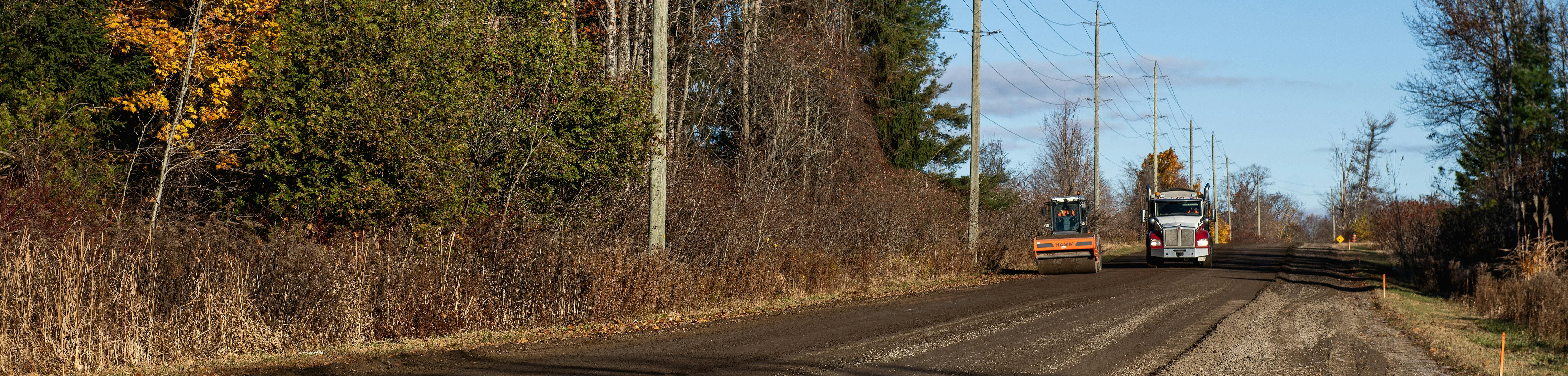 Trucks repaving rural road
