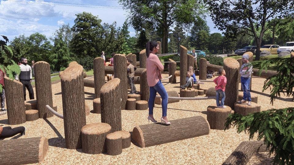 Ground-level perspective of climbing structure showing log beams, ropes, and pull-up bars to encourage sensory play.