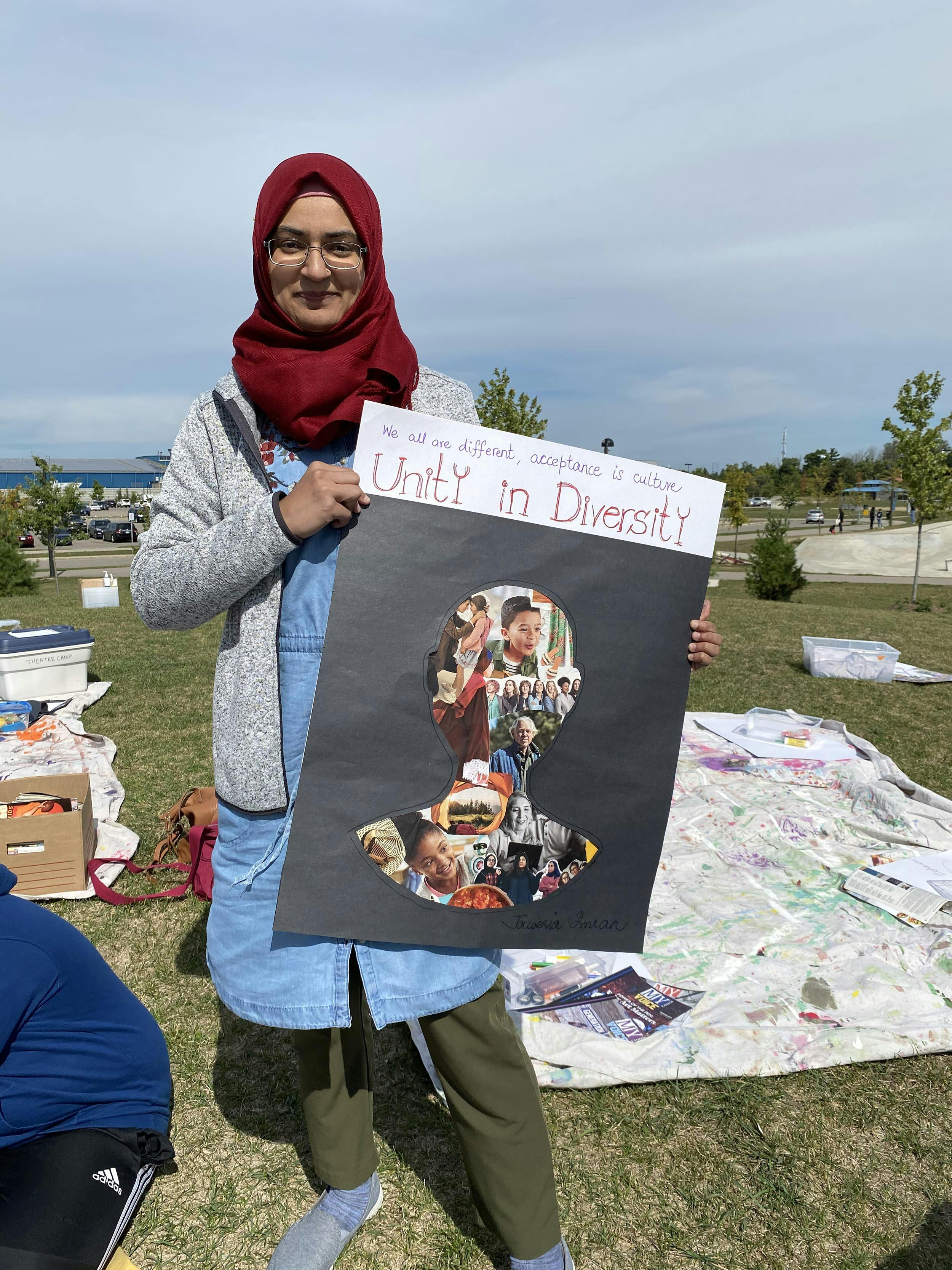 Jaweria showing her artwork - a collage of people demonstrating unity in diversity. 