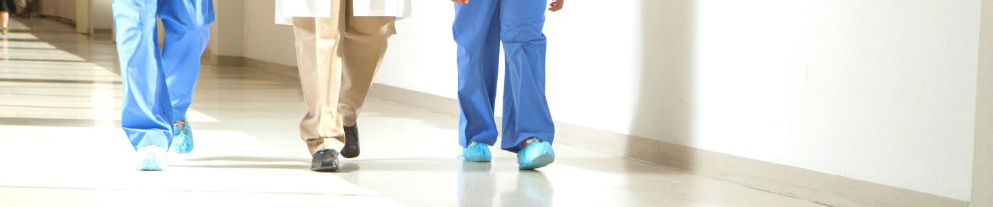 Image of three health care providers walking through the hallway of a hospital.