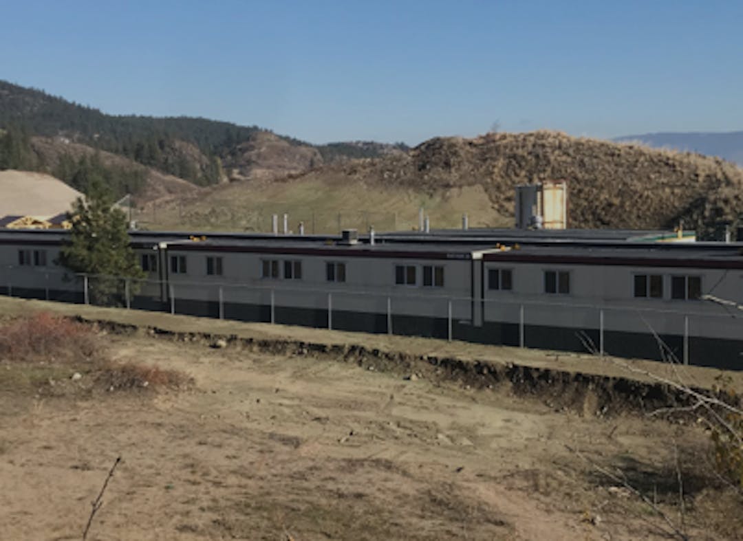 A row of trailer homes with a mountain in the background and dirt in the foreground.