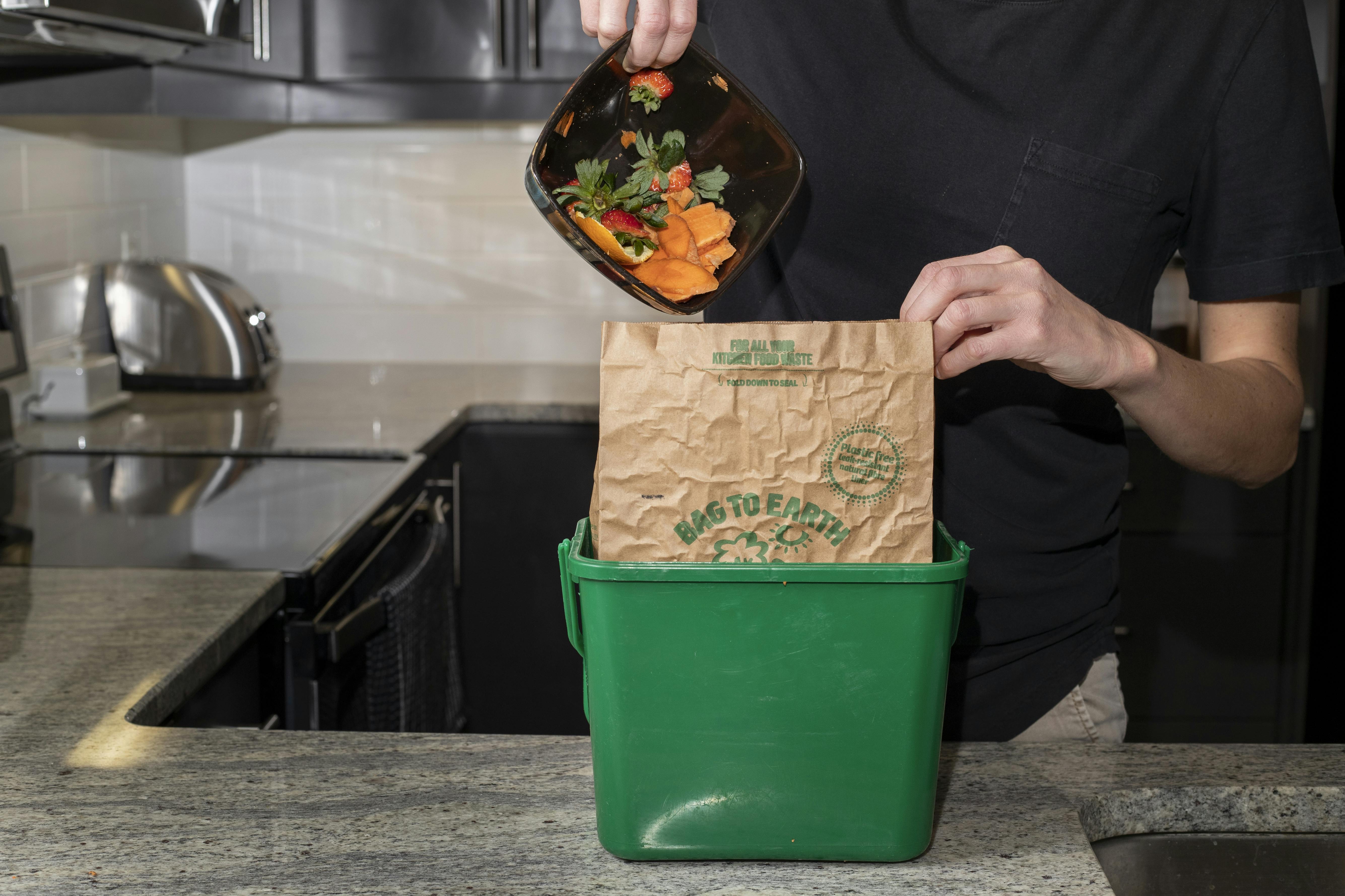 Organic materials like vegetable skins being placed in the kitchen container