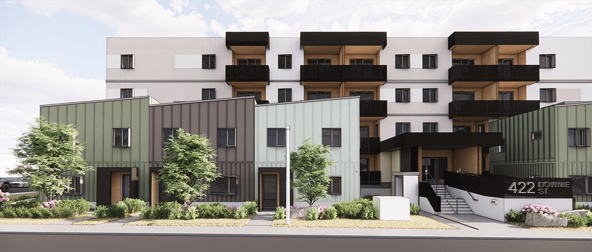 A modern residential complex featuring a row of green and gray townhomes in the foreground with landscaped greenery, and a four-story apartment building with black balconies in the background. The entrance displays the address “422 Downie St.”
