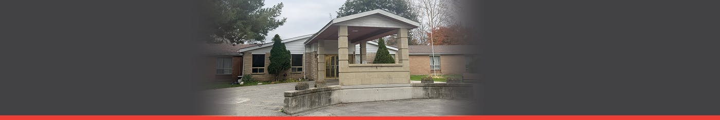 An exterior photo of a grey and red brick building with a large banner sign that says Fox Ridge