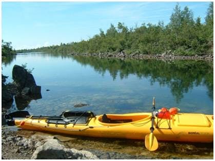 Image of the River Canard Kayak Launch, a yellow kayak in the foreground, River Canard in the middle ground and trees in the background.