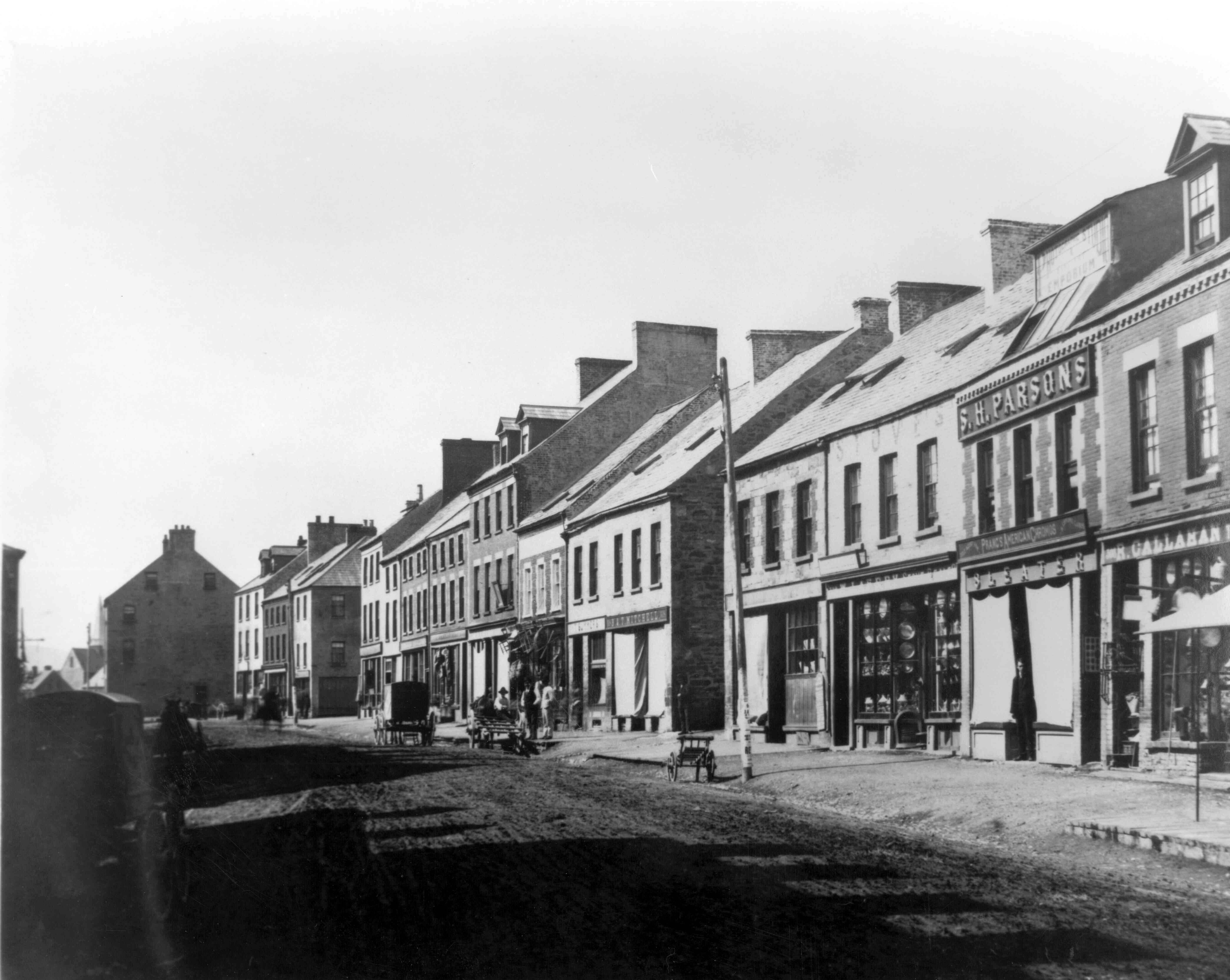 1890's: Water Street looking west showing the premises of R. Callahan, S.H. Parsons, B & T Mitchell, and others