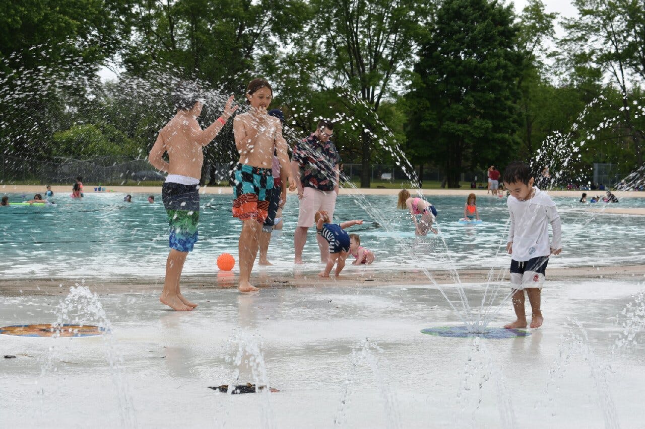 Children playing among spray features beside pool