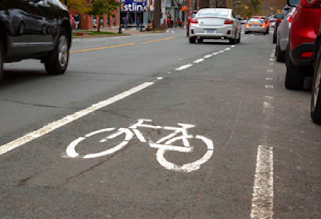 Current South Park Street bike lane near the Spring Garden Road intersection, with cars parked on the right hand side and road traffic on the left hand side. 