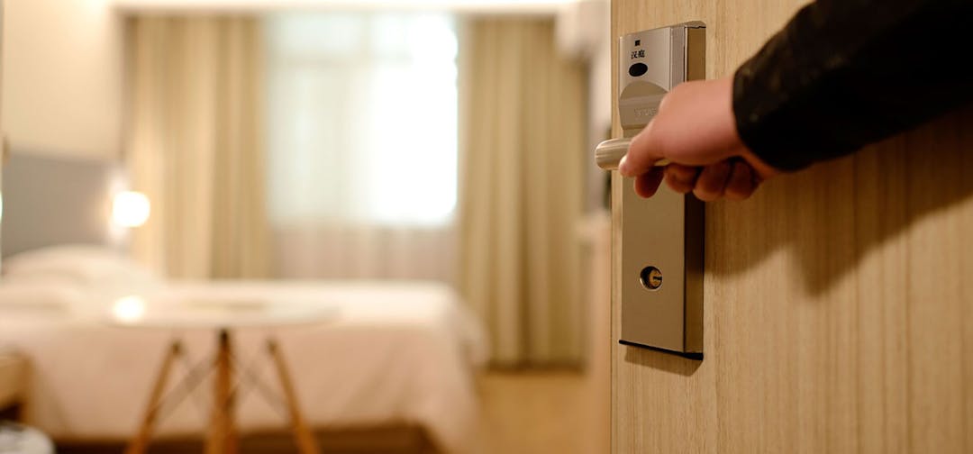 Hotel door opening image of hand opening a hotel door