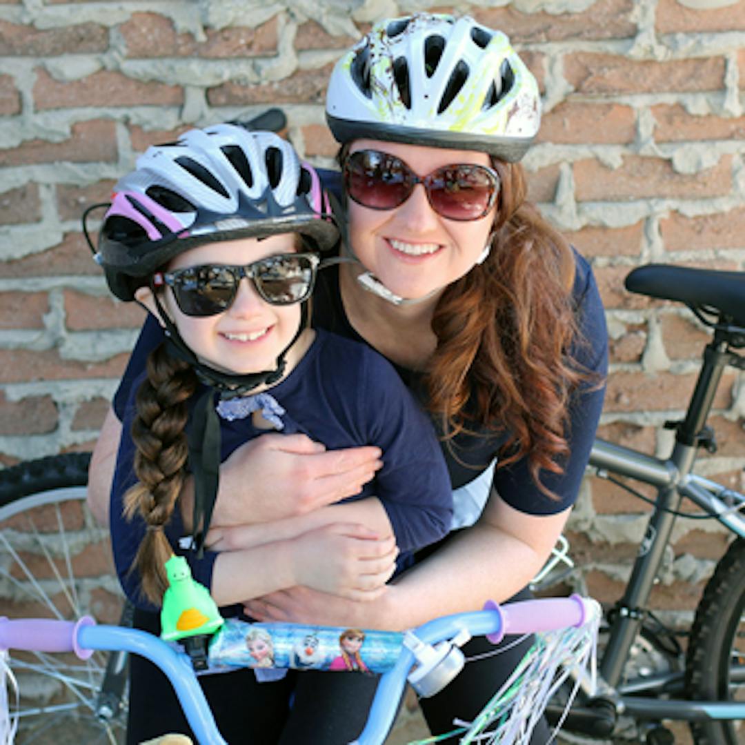 Mother and child with their bikes and bike helmets getting ready to cycle.