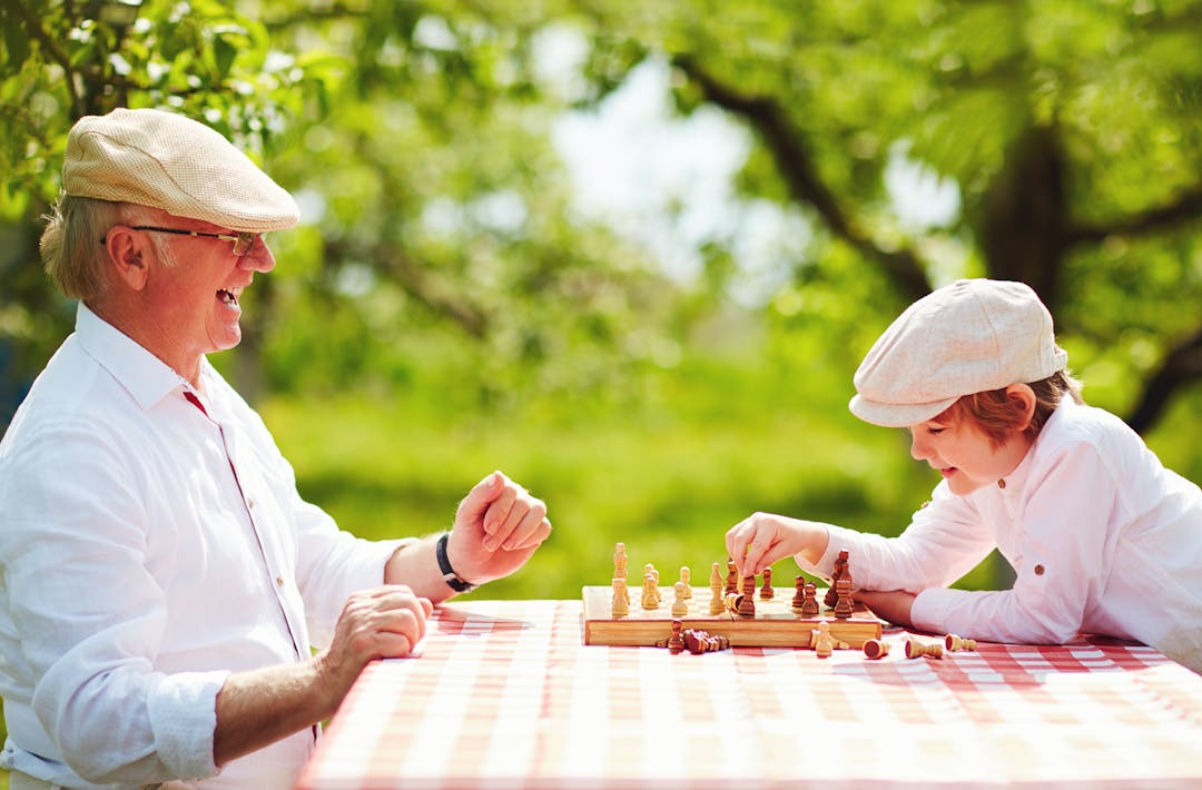Playing in the park Senior gentleman and boy playing chess in the park