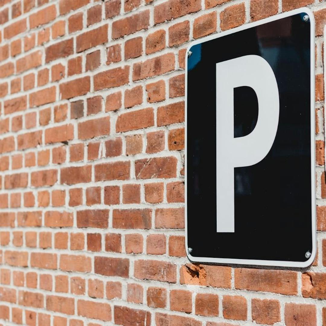 Black and white parking sign on brick wall