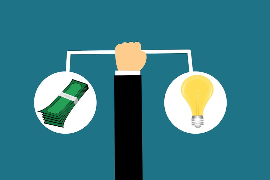 Let's Talk Budget A hand is holding a bar with money on one end and a light bulb on the other